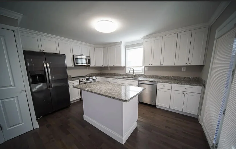 Completed kitchen remodel with white cabinets, island and stainless steel appliances