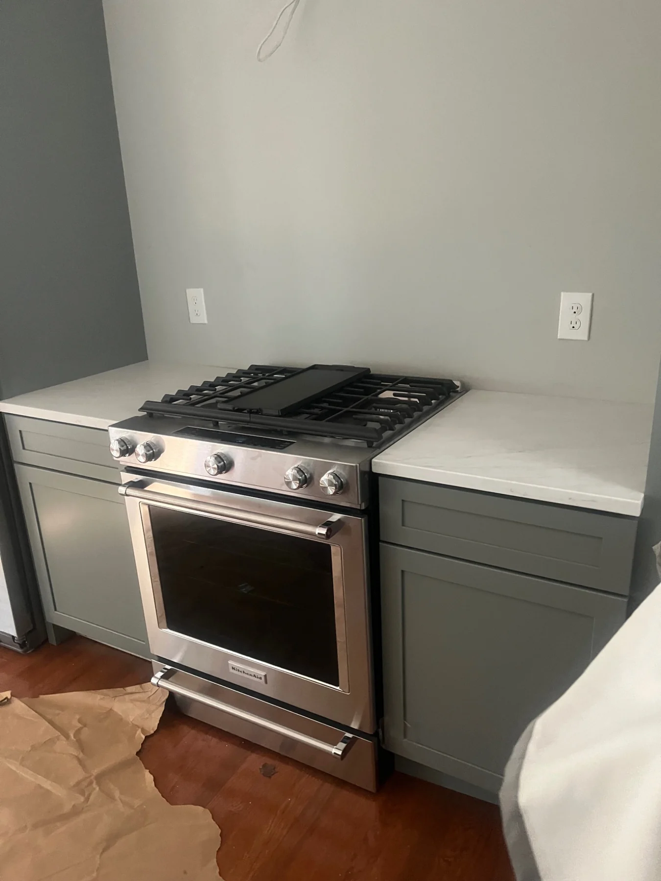 Completed kitchen with gray cabinets, quartz counters and stainless steel range